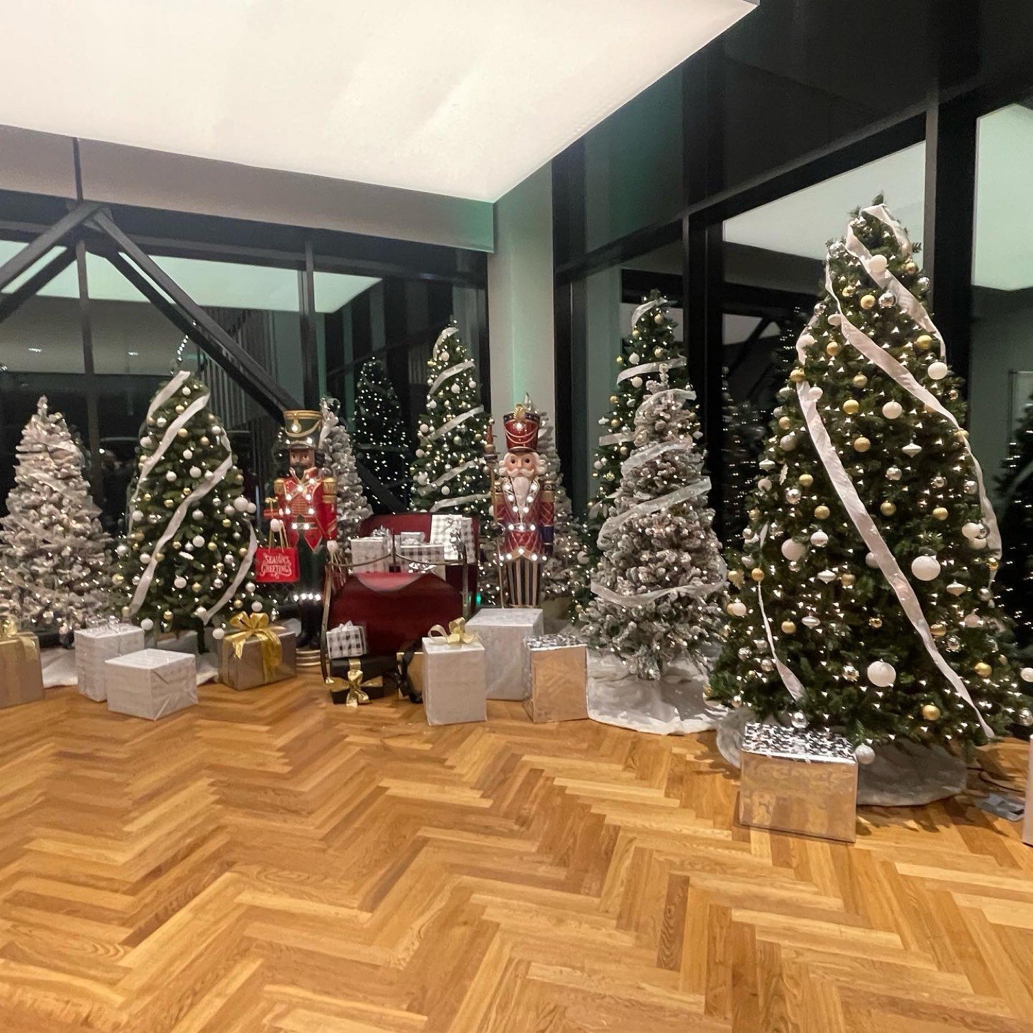 Lobby grove of flocked and green trees with nutcrackers and gifts